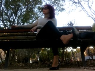 I am dangling my black pumps and my leather pants on a bench in the park
