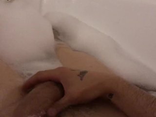 The guy jerks off taking a bath with foam