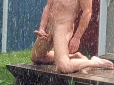 Fit, hung dude jerks off fully naked in the garden, in the pouring rain gif