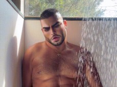 HornyRicanBoi strokes his uncut cock and cums on his abs in the shower gif