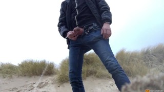 young man urinates in the dunes