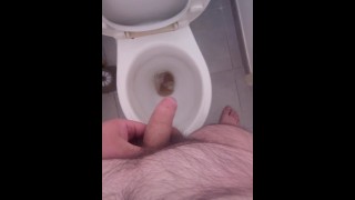 Jeune mec poilu pisse aux toilettes