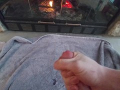 Young guy jerks off in front of fireplace on a cold day