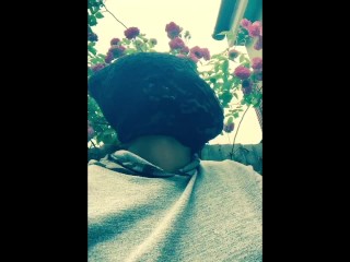 Чернокожая толстушка в маске курит на улице в саду и трет киску