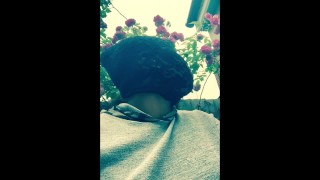 Чернокожая толстушка в маске курит на улице в саду и трет киску
