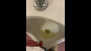 Orinando y masturbándose en un urinario público