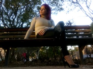 I am dangling my black pumps and my leather pants on a bench in the park
