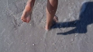 Knappe tiener krijgt haar voeten nat op het modderige strand