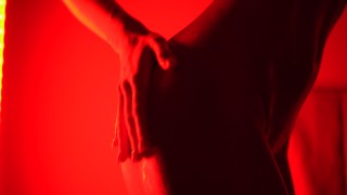 ウィークエンドの音楽に赤い光の中でオイルダンスをしているソロのヌードの女の子