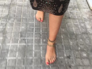 young female hippie is walking barefoot in public street