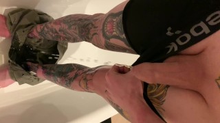 Татуированный парень отчаянно мочится, снимая шорты и боксеры