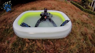 Rufus pawing off in wetsuit, fins and pool