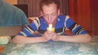 Magere tiener duwt banaan diep in zijn keel
