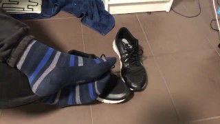 Male shoeplay in striped socks and different sneakers and watching a movie