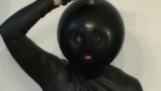 Девушка в латексном комбинезоне с черным резиновым капюшоном мастурбирует своей киской