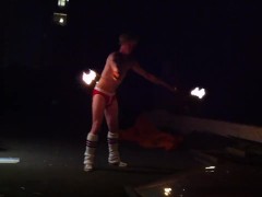 Blond guy spins fire on rooftop in socks and underwear