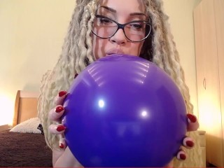 Большой фиолетовый шар дует, чтобы лопнуть в прозрачном сексуальном платье