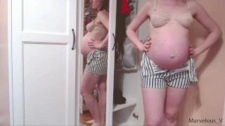 Hot mamá embarazada sexy probándose su ropa apretada en el vientre enorme