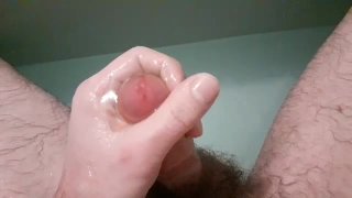 Primer plano de mastrubación masculina y juego de pis en el baño con doble eyaculación