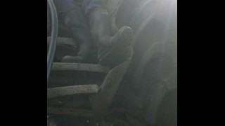 Il fusto rasato in stivali di gomma si siede e lavora su un carico caldo sui gradini del trattore