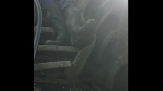 Hunk afeitado en botas de goma se sienta y trabaja una carga caliente en los pasos del tractor