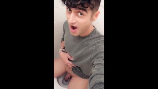 Twink pinkelt mit seinem unbeschnittenen Schwanz in sitzender Position auf eine Toilette