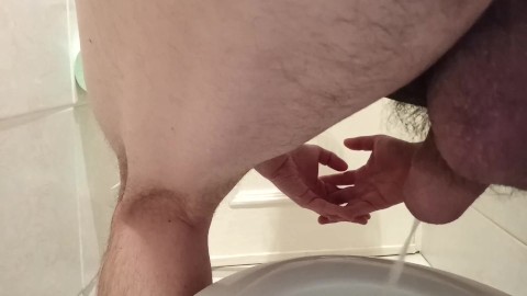 Pissing in toilet. Rear ball view