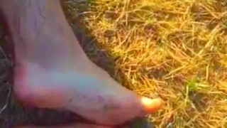 Solo guy rubbing feet in dirt outdoors