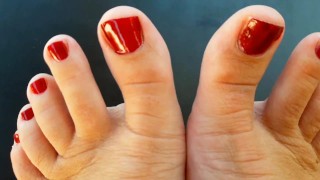 Red nail polish on toes. lady paints her toenails with red polish Regina Noir.