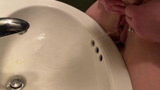 Moglie piscia nel lavandino in un bagno pubblico