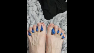 Magere jongen spreidt zijn sexy voeten vingers en masseert zijn voeten