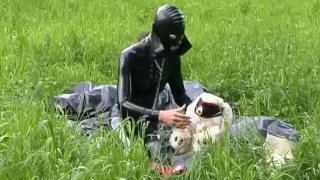 黒いラテックスキャットスーツとマスクでいっぱいのゴムの女の子が牧草地で屋外で遊ぶ-パート1