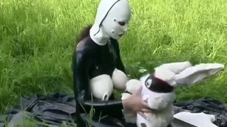 Rubber meisje volledig in Black latex catsuit en masker speelt met zichzelf buiten in een Meadow - Deel 3