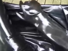 Latex girl full in black rubber and Gasmask chill outs outdoor in garden in a heavy rubber hammock