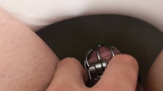 Guy dans Chastity fait pipi dans les toilettes