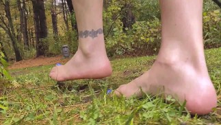 Зрелая мама-хозяйка в четверг гуляет босиком на открытом воздухе под дождем по мокрой траве с грязными ногами