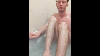 Magere tiener neemt een bad en gebruikt shampoo om zichzelf te wassen