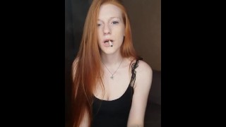 A Young Woman With Long Red Hair Smokes A Cigarette Inhaling Deeply