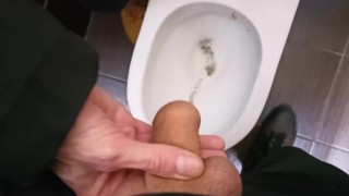 In a public place, my femboy slut holds my dick and I piss in a dirty urinal