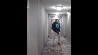 タイツのアスリートはホテルのホールで彼のコックを取り出します