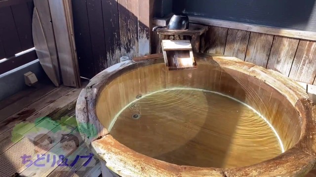 Японская женщина-любительница неторопливо принимает ванну в гостинице с горячими источниками с ванной под открытым небом.