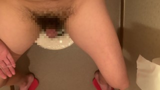 Masturbación sentada en el asiento del inodoro en el baño.