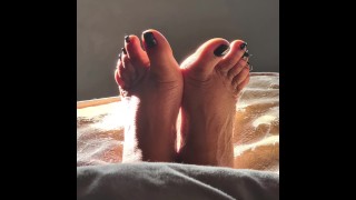 自然な日光の下で黒い塗られた爪で私の足
