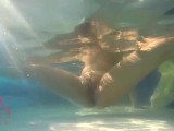 Elegant and flexible babe, swimming underwater in the outdoor swimming pool.