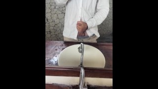 Jonge man in een shirt masturbeert dikke lul door een spiegel