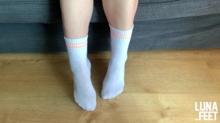 Chica sexy muestra sus bonitos calcetines deportivos blancos después de caminar