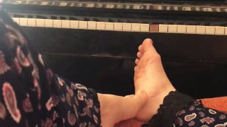 Wonderful feet of the girl on the background of the piano