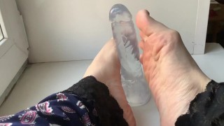 foot fetish. beautiful legs and a transparent dildo, on the windowsill