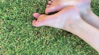草の上で外で私の足と汚れた足の爪で遊ぶ
