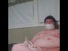 Fat male gagged with hand taped to leg masturbating